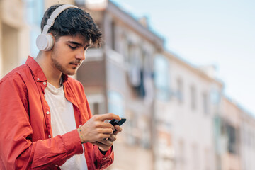 Poster - young man on the street with mobile phone and headphones