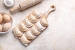 © Alona Dudaieva - Raw dumpling with potatoes. Preparation dumplings on a light background on a wooden board. Fresh, handmade Ukrainian dumplings. National traditions, masna. Homemade dough products, craft cooking.