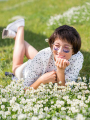 Wall Mural - Woman in colorful sunglasses sniffs clover flowers on lawn in urban park. Nature in town. Relax outdoors after work. Summer vibes.