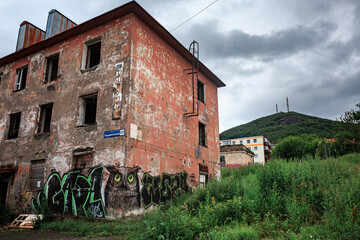 A ruined building in Kamchatka against the backdrop of a mountain, a house without windows.