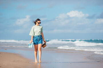 Wall Mural - Young happy woman walking on the beach 