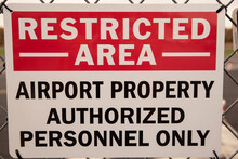 Restricted area sign for airport on chain link fence