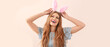 Beautiful young woman with Easter bunny ears on beige background