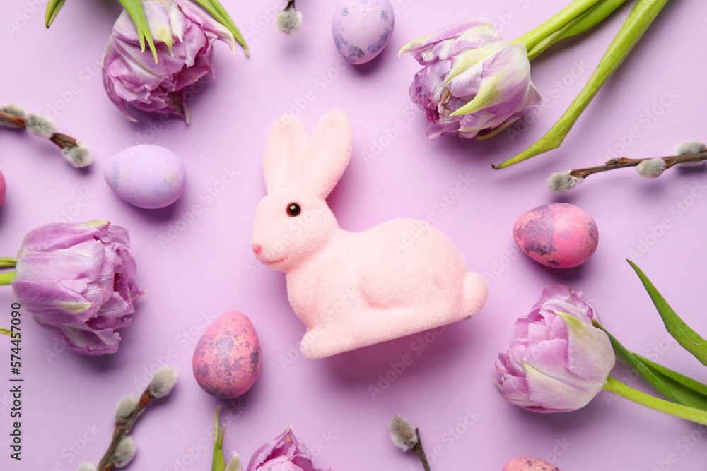 Composition with Easter bunny, tulip flowers, pussy willow branches and painted eggs on lilac background