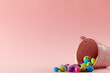 Image of multi coloured easter eggs, pink bucket with copy space on pink background