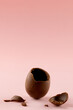 Image of broken chocolate easter egg and copy space on pink background