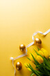 Image of gold easter eggs with yellow tulips and copy space on yellow background