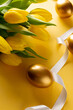 Image of gold easter eggs with yellow tulips and copy space on yellow background