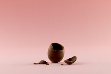 image of broken chocolate easter egg and copy space on pink background