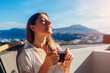 Woman relaxing on hotel terrace drinking morning coffee enjoying Santorini mountain landscape. Breakfast with view