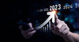 Fototapeta  - Business growing in 2023. Analytical businessman planning business growth 2023, strategy digital marketing, profit income, economy, stock market trends and business