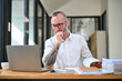 © bongkarn - Focused caucasian businessman with tattoo on his arm is working on financial data on laptop