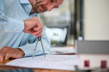 Wall Mural - Professional Caucasian male engineer using a divider compass, drawing scale on a blueprint