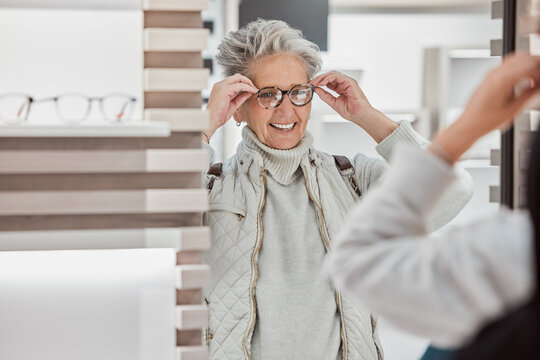 Senior woman, glasses and eye care at mirror with patient shopping for vision lens or frame in optics shop. Happy customer person smile for decision on optometry product choice for eyes and wellness