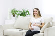 © Andrii - Pregnant woman sitting on white sofa and touching her stomach.