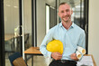 © Prathankarnpap - Portrait of handsome engineer man holding yellow helmet and blueprint standing in office. Engineer, construction concept