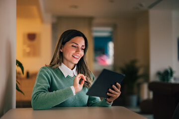 Smiling businesswoman having an online meeting with a colleague, using a digital tablet.