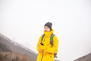 Wall Mural - The man dresssed yellow warm jacket and trousers, bagpack traveling in the snow landscape