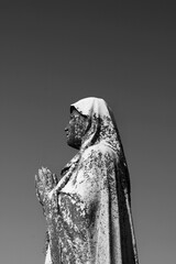 Sticker - A statue of the Virgin Mary with hands in prayer in a black and white.