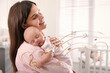 Mother singing lullaby to her baby at home. Music notes illustrations flying around woman and child