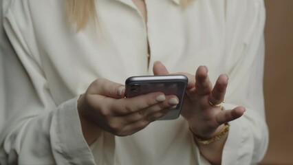Businesswoman with smartphone typing a message. Cropped view of a stylish woman texting quickly on the phone screen. Elegant girl messaging someone