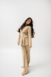 © LIGHTFIELD STUDIOS - full length of barefoot woman with long hair posing in fashionable pantsuit on grey background.