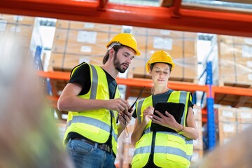 Warehouse worker standing check stock quantity of product and key information to tablet pc