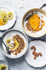 Wall Mural - Yogurt granola bowls with kiwi and orange fruits,  top view. Healthy vegetarian breakfast meal