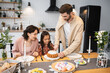 © LIGHTFIELD STUDIOS - Man cutting Easter bread near wife and daughter at home.