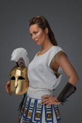 Wall Mural - Shot of brown haired female soldier from ancient greece holding plumed helmet.