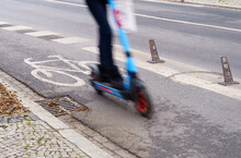 A Woman Travels On An Electric Scooter Along A Bicycle Path.
