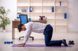 © Elnur - Young male employee doing sport exercises during break