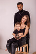 © Natasha  - A happy stylish multi-racial family in black clothes, sitting in light room