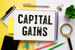 Capital gains - increase in a capital asset's value and is realized when the asset is sold, text concept on notepad.