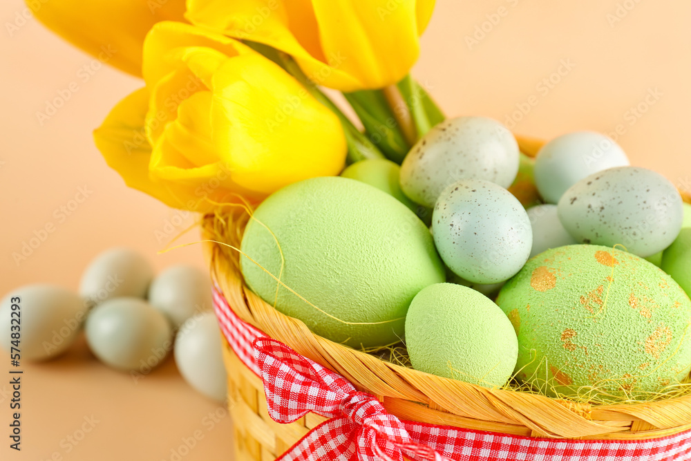 Basket with beautiful Easter eggs and tulip flowers on color background, closeup