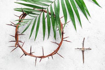 Crown of thorns with wooden cross and palm leaf on white background. Good Friday concept