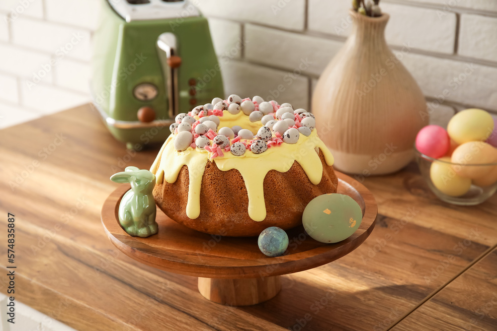 Dessert stand with Easter cake, painted eggs and bunny on kitchen counter