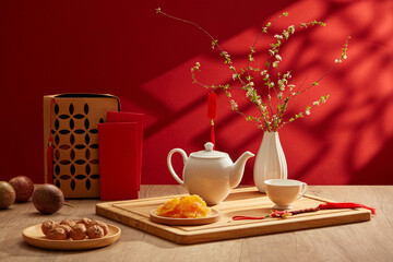 Wall Mural - A tea set placed on wooden tray with dried candy and flower pot. Red-themed background for new year concept. Chinese new year