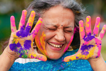 Wall Mural - Indian senior woman playing colors and celebrating holi festival.