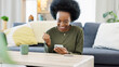 © Nina L/peopleimages.com - Excited black woman chatting in dating app using her phone at home. A young female online shopping happy about a purchase in her house. A lady celebrating after reading good social media news