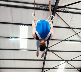 Canvas Print - Man, acrobat and gymnast turning on rings in fitness for practice, training or workout at gym. Professional male gymnastics hanging on ring circles for athletics, balance or strength exercise indoors