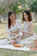 © Phushutter - Two pretty asian friends woman picnic at park outdoor in relax time holiday, holiday recreation concept.