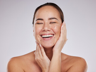 Canvas Print - Skincare, hands on face and woman laughing in studio for cosmetics, dermatology and beauty glow. Happy aesthetic asian model person with makeup, skin mole and facial self care on grey background