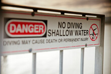 A Sign Warning Users Not To Dive Into The Shallow Water.