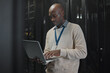 © Kirsten D/peopleimages.com - Laptop, server room and black man or technician in data center management, system or cybersecurity. Analysis, serious or power coding solution, engineering programmer or information technology person