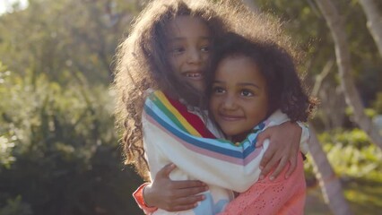 young cheerful siblings posing outdoors, hugging and looking at camera and smile. realtime