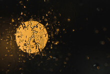 Background With Water Drops On Glass Against Obscure Yellow Ray In Darkness
