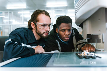 Specialist robotic engineers maintenance and control robot arm in factory warehouse, Testing new innovation automation robot for industrial.African american and caucasian man teamwork working together