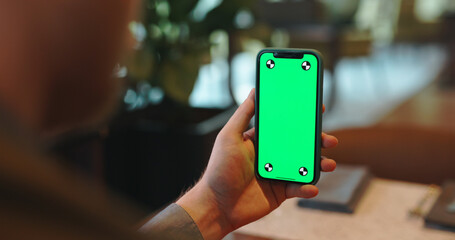 Wall Mural - Smart phone with green chroma key mock up screen in office cafeteria. Close up shot of digital device display - technology concept 
