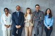 © Dragana Gordic - The business people standing on the gray wall background. Business team headed with boss, posing to camera over grey wall in office. Diverse businesspeople smiling at the camera